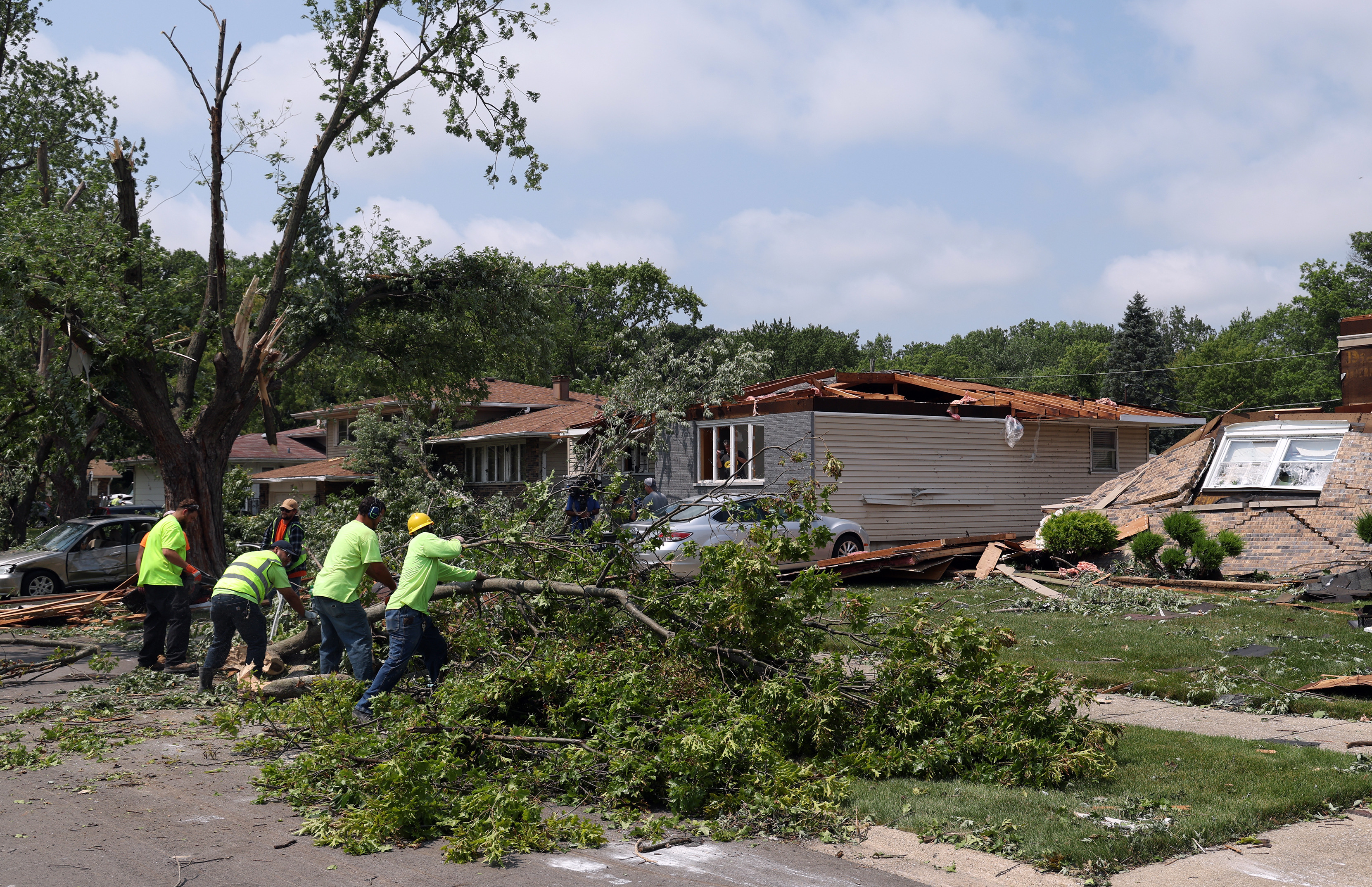 Workers clear debris from 192nd Place west of Oakwood Avenue in Lansing, July 28, 2026, a day after storms. (Terrence Antonio James/Chicago Tribune)